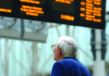 Elderly person looking at train departures/arrivals screen